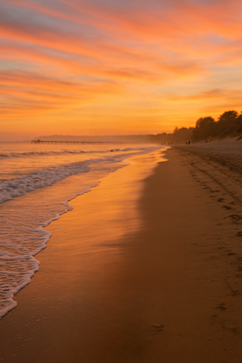 Sunset beach with golden skies and distant pier
