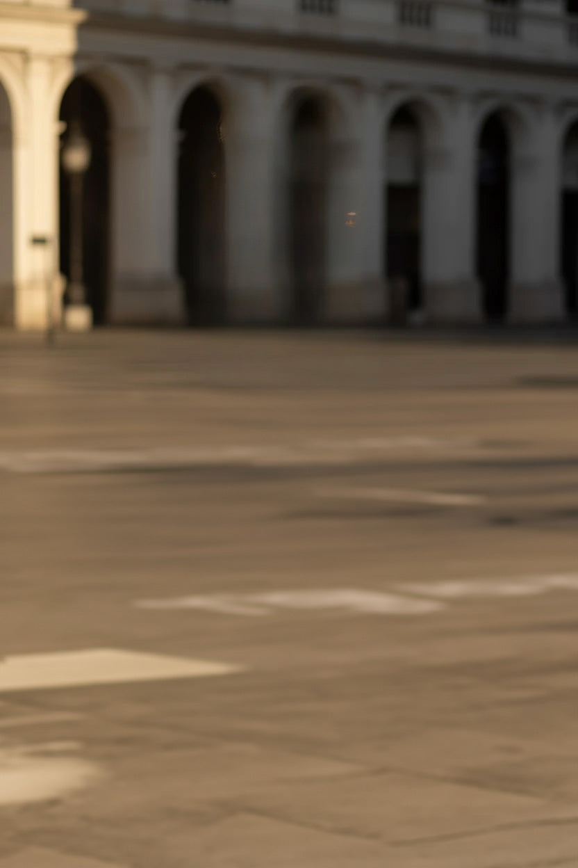 Sunlit plaza with stone pavement and arched building facade