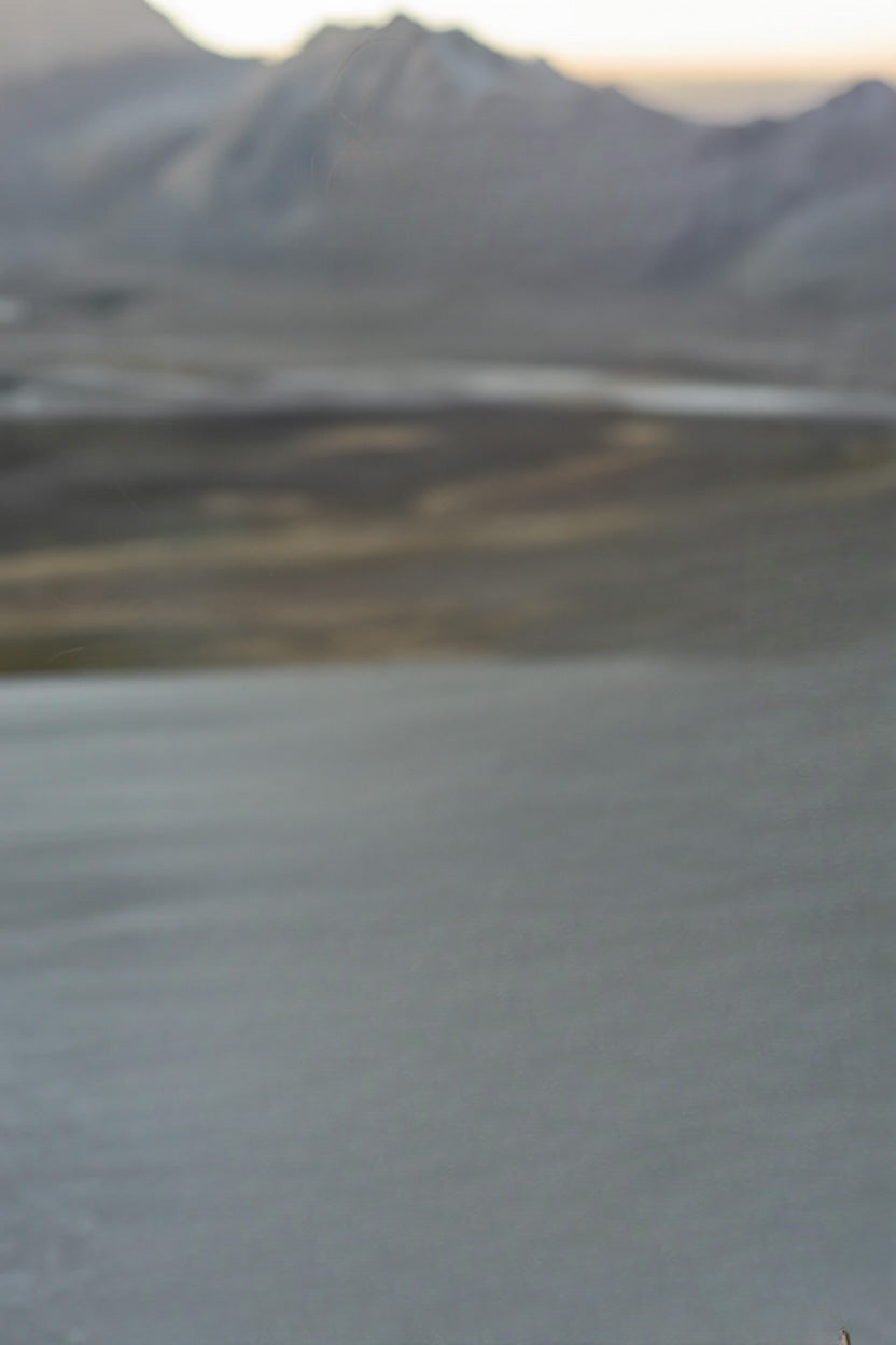 Calm lake with distant mountain range under soft light