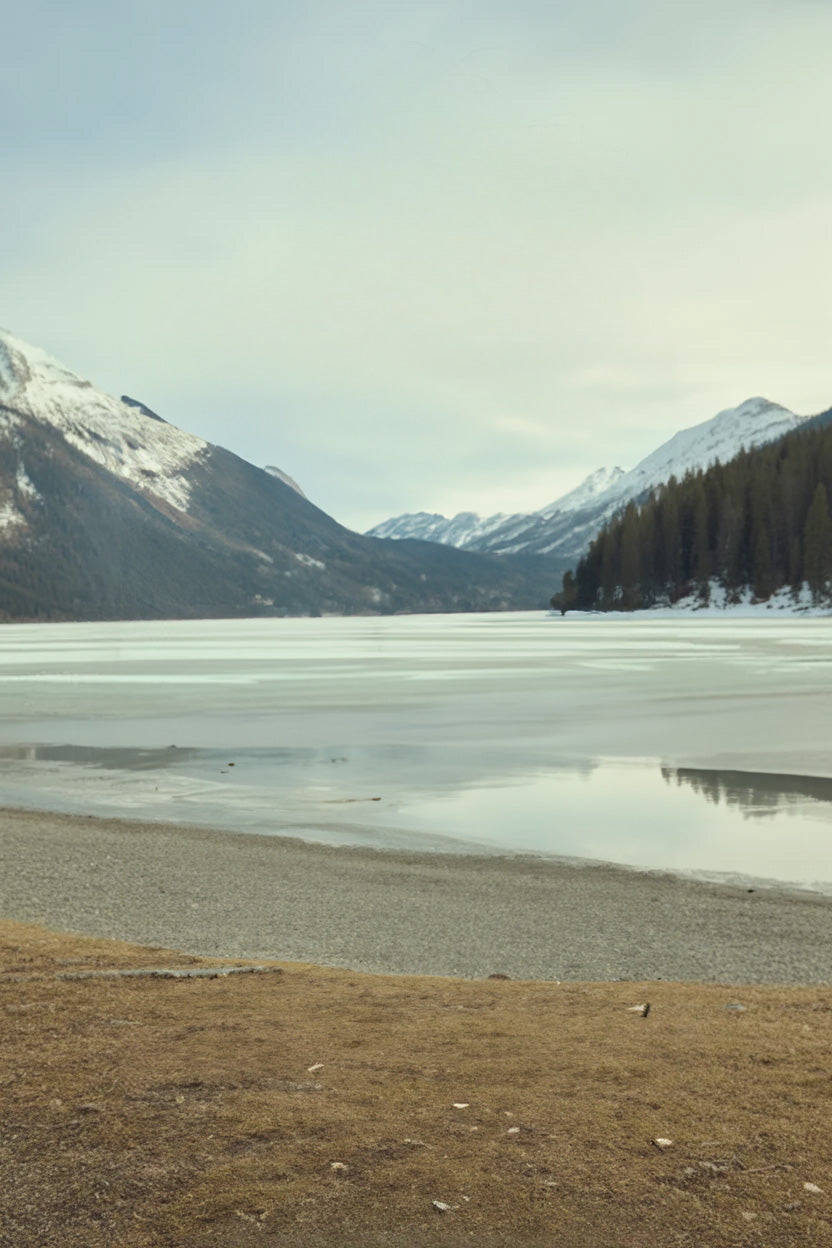 Frozen mountain lake surrounded by snow-covered peaks and forest