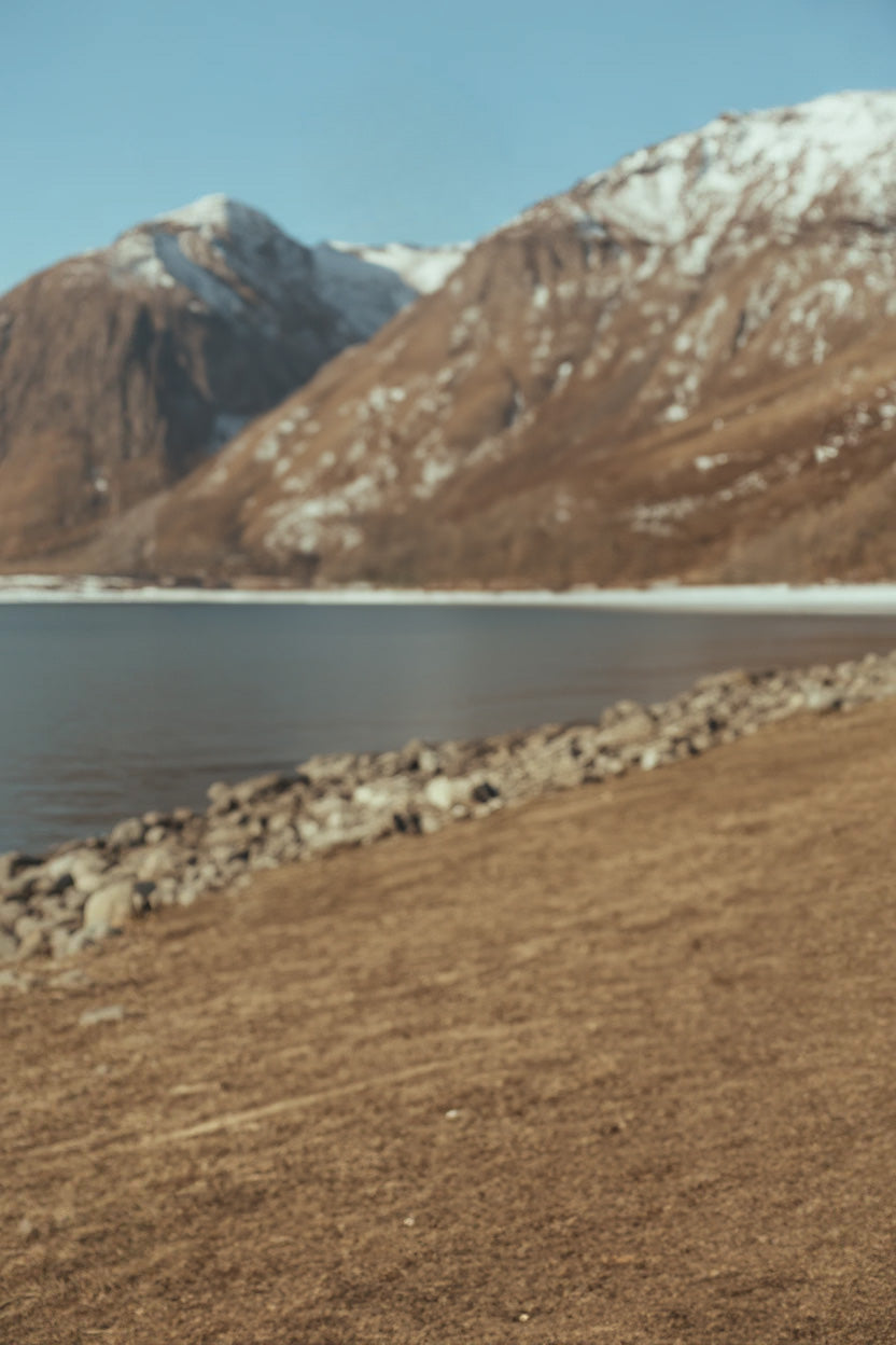 Rocky lakeshore with snow-capped mountains in the distance