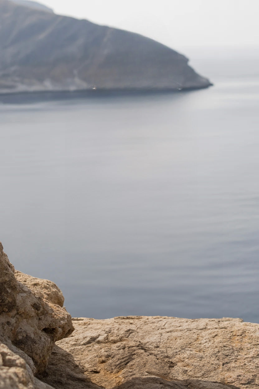 Rocky coastal cliff overlooking calm sea and distant headland