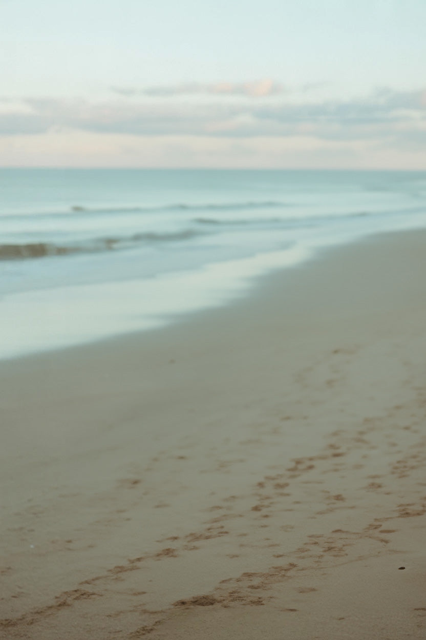 Tranquil sandy shoreline with gentle waves and clouds