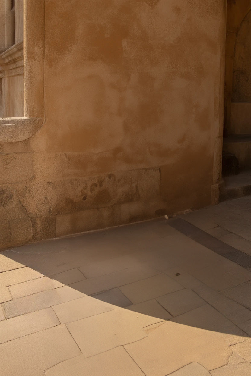Warm stone wall with curved shadows on tiled pavement