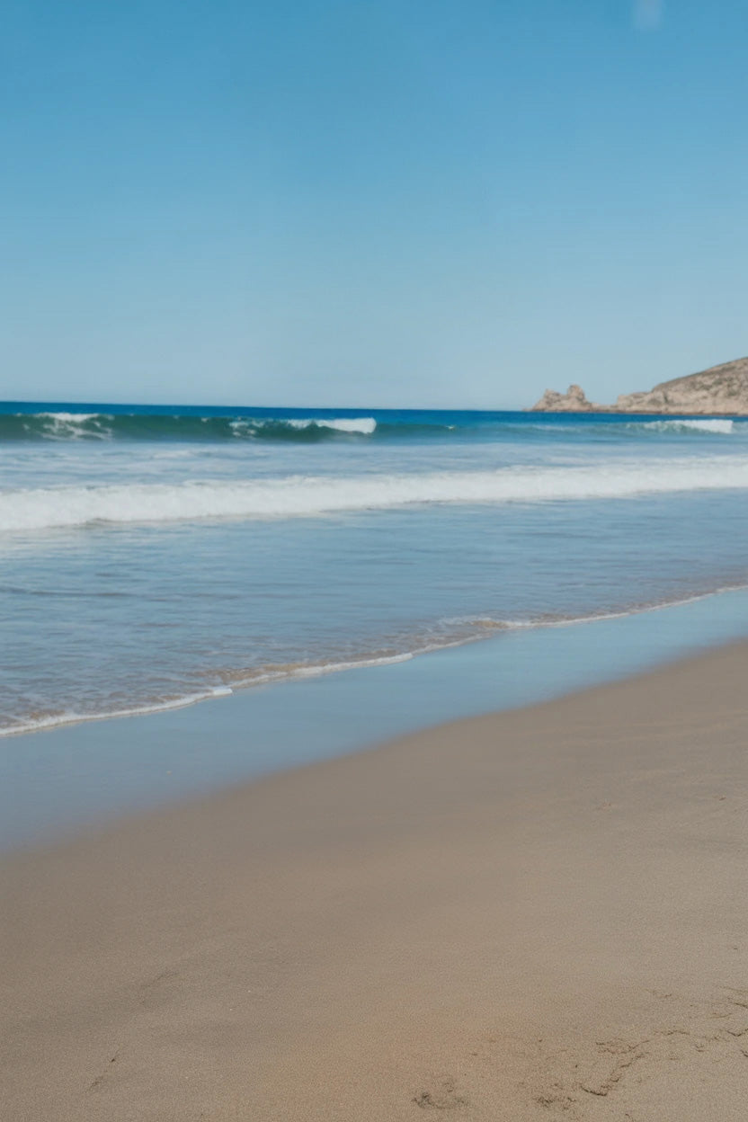 Sandy shoreline with gentle ocean waves and blue sky