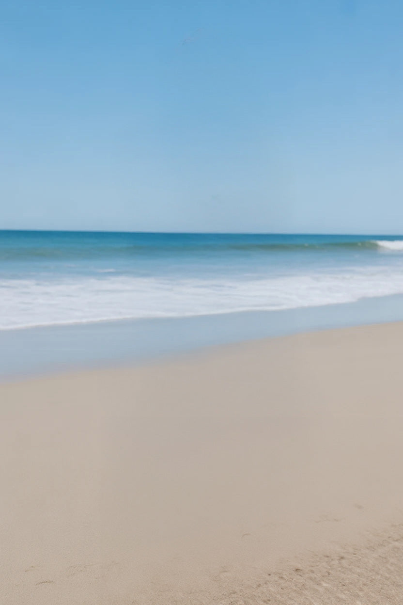 Calm sandy shoreline with gentle waves and clear sky