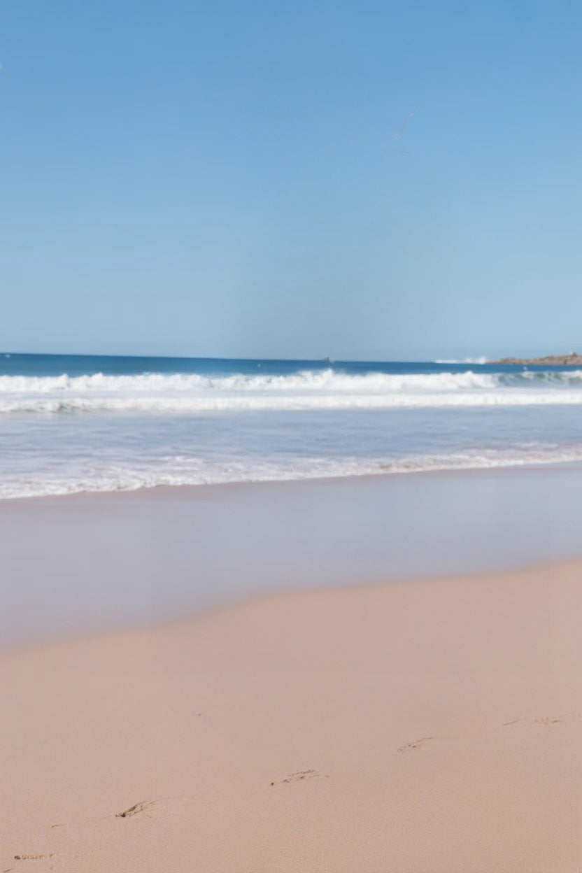 Calm sandy shoreline with gentle ocean waves under blue sky