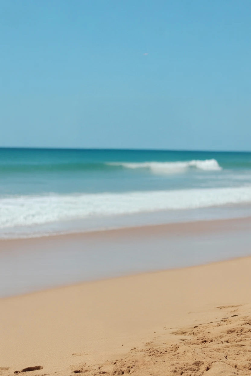 Golden sandy beach with gentle waves and clear sky