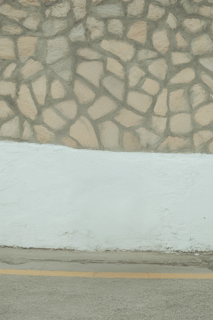 Stone patterned wall with white base and sidewalk edge