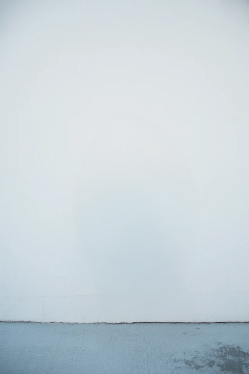 Plain white wall with slightly textured concrete floor