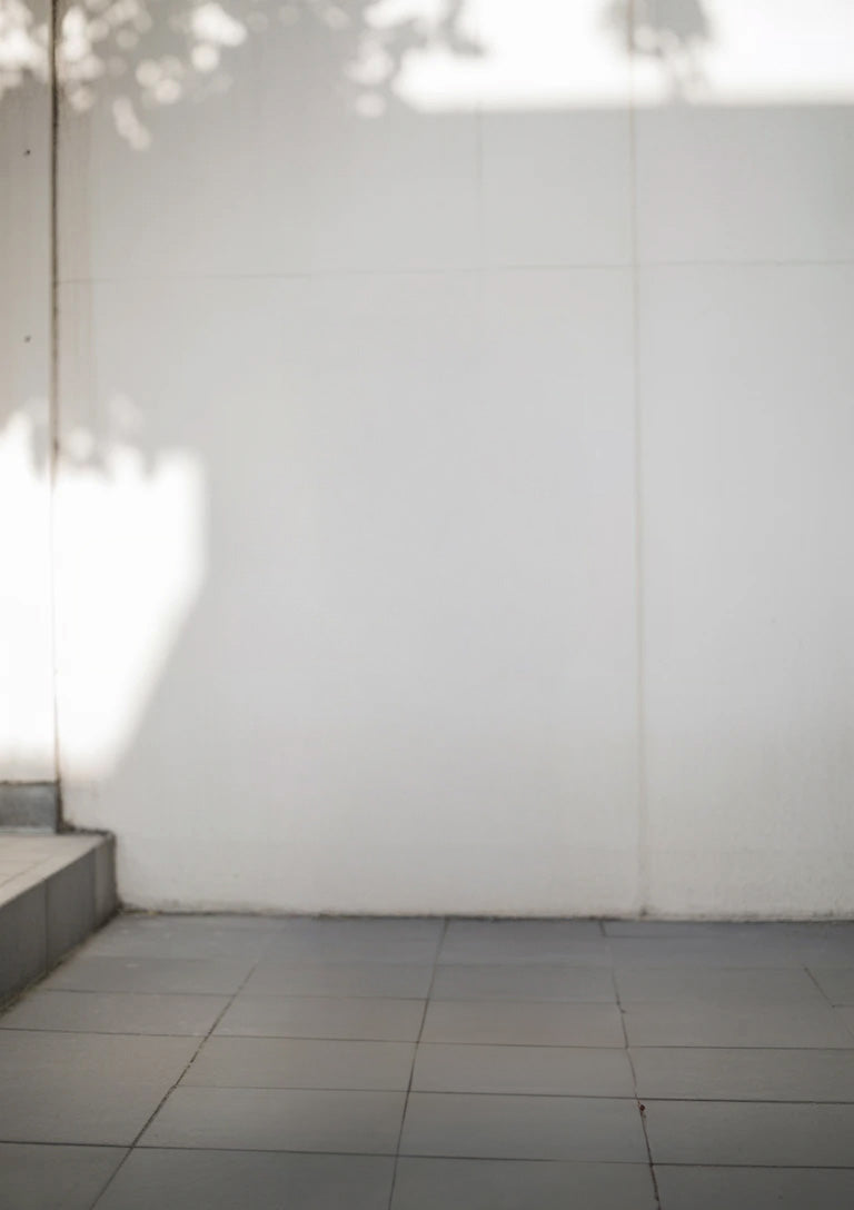 Minimalist tiled floor with white wall and soft sunlight shadows