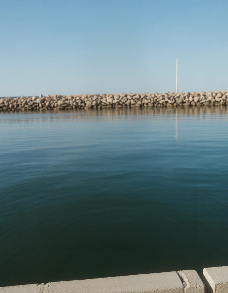 Calm waterfront with rock barrier and clear blue sky