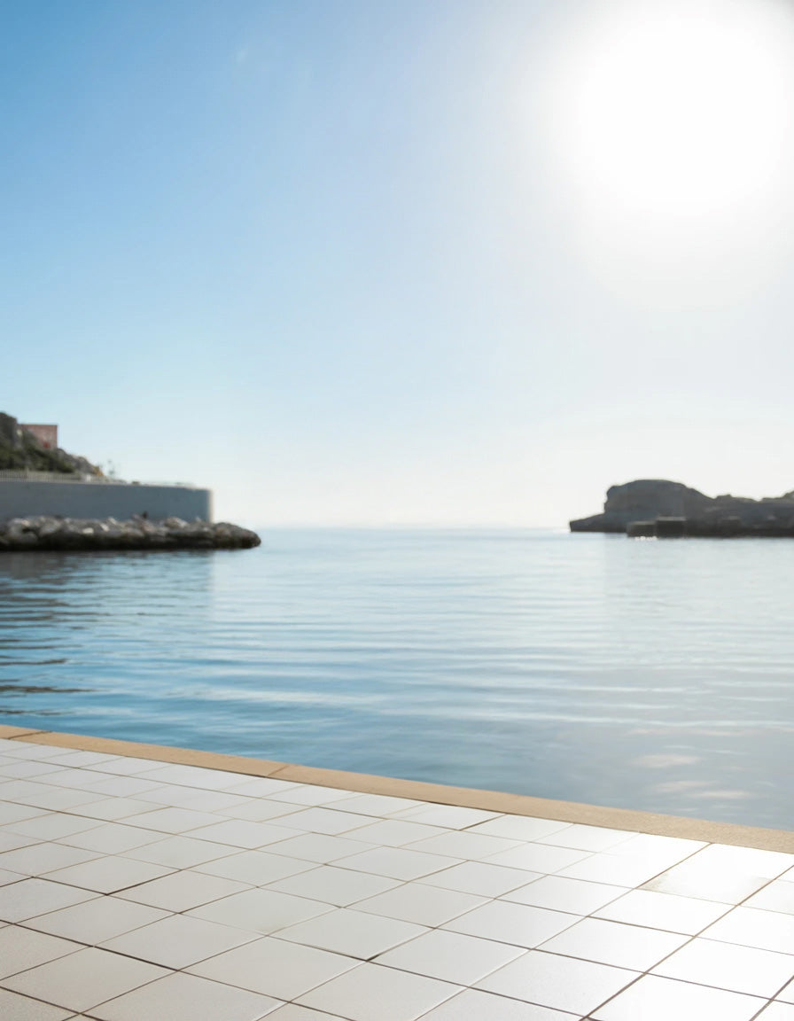 Tile terrace overlooking calm water with bright sunlight