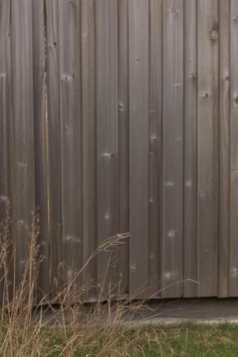 Weathered wooden fence with dry grass at the base