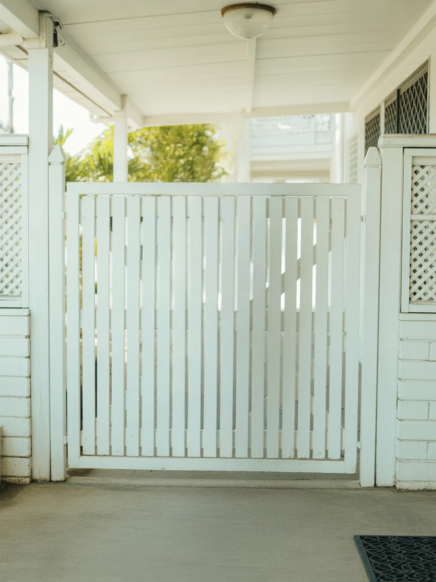 White wooden gate with lattice panels and covered porch