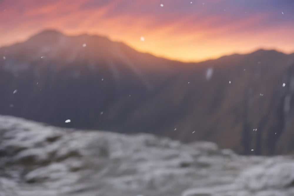 Snowy mountain landscape with sunset sky and falling snowflakes