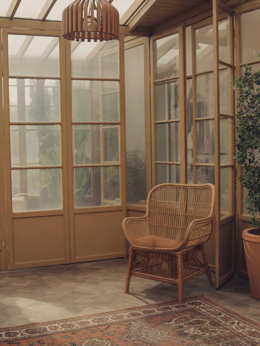 Cozy sunroom with wooden framed windows and wicker chair
