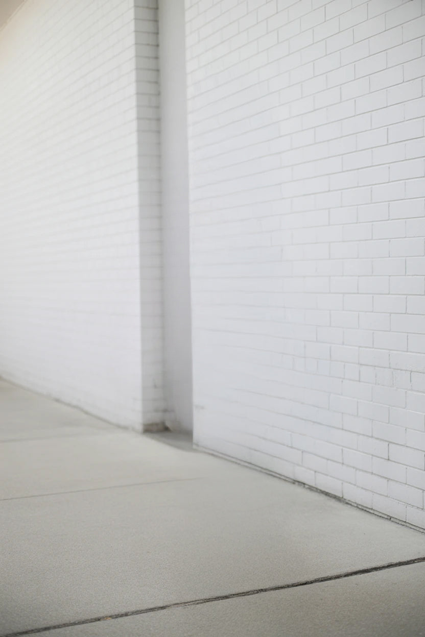 White brick wall with clean smooth concrete sidewalk