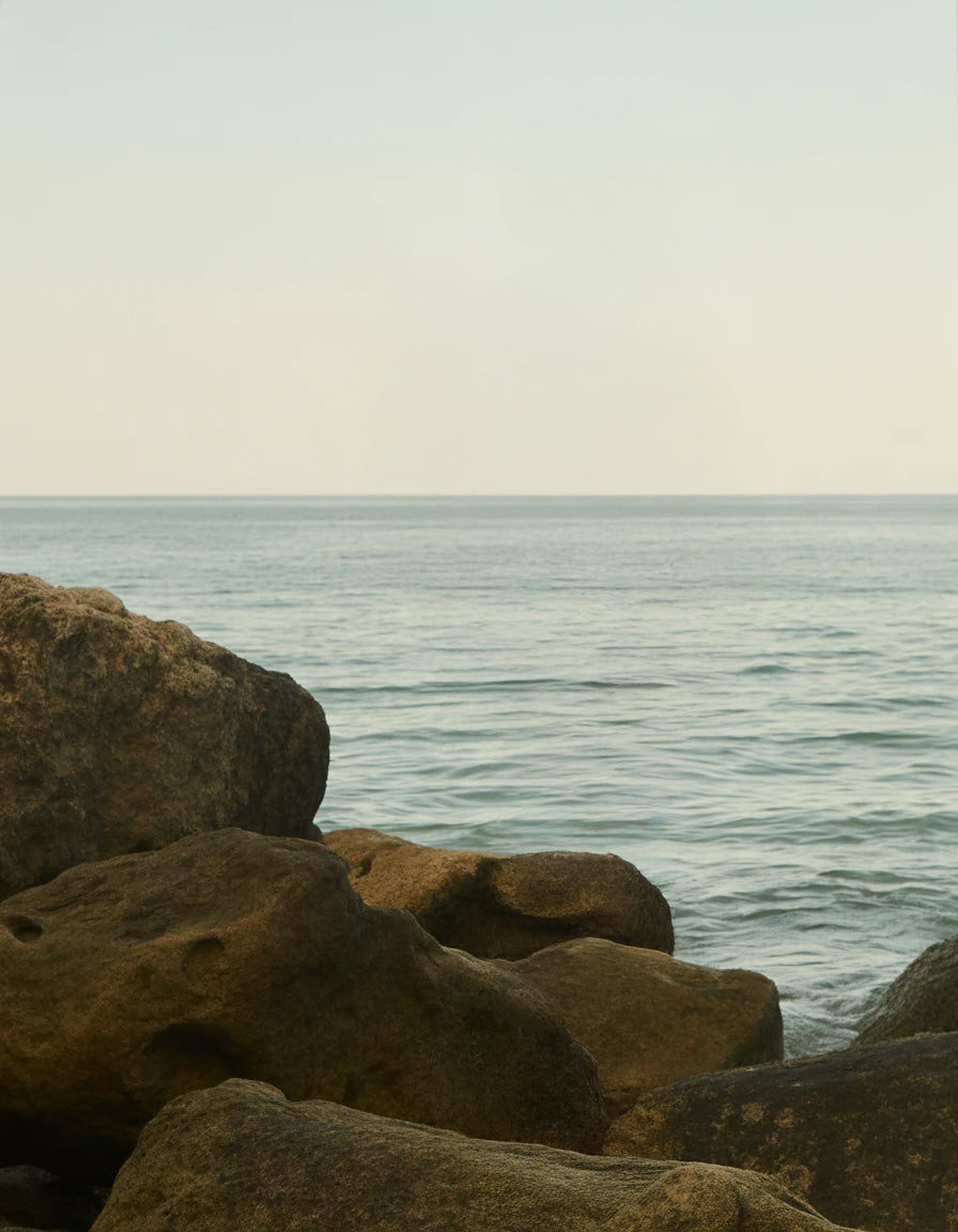 Large weathered rocks by calm sea under soft light