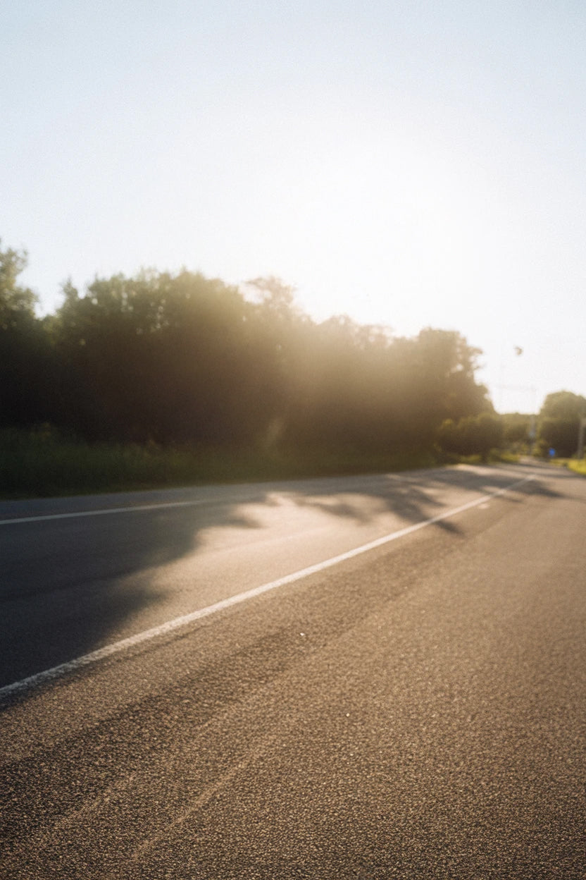 Sunlit asphalt road with tree shadows and clear sky