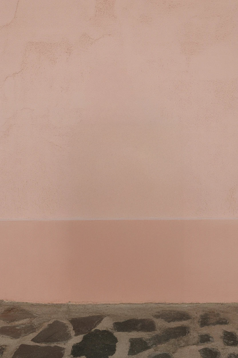 Soft pink stucco wall with dark stone pavement base