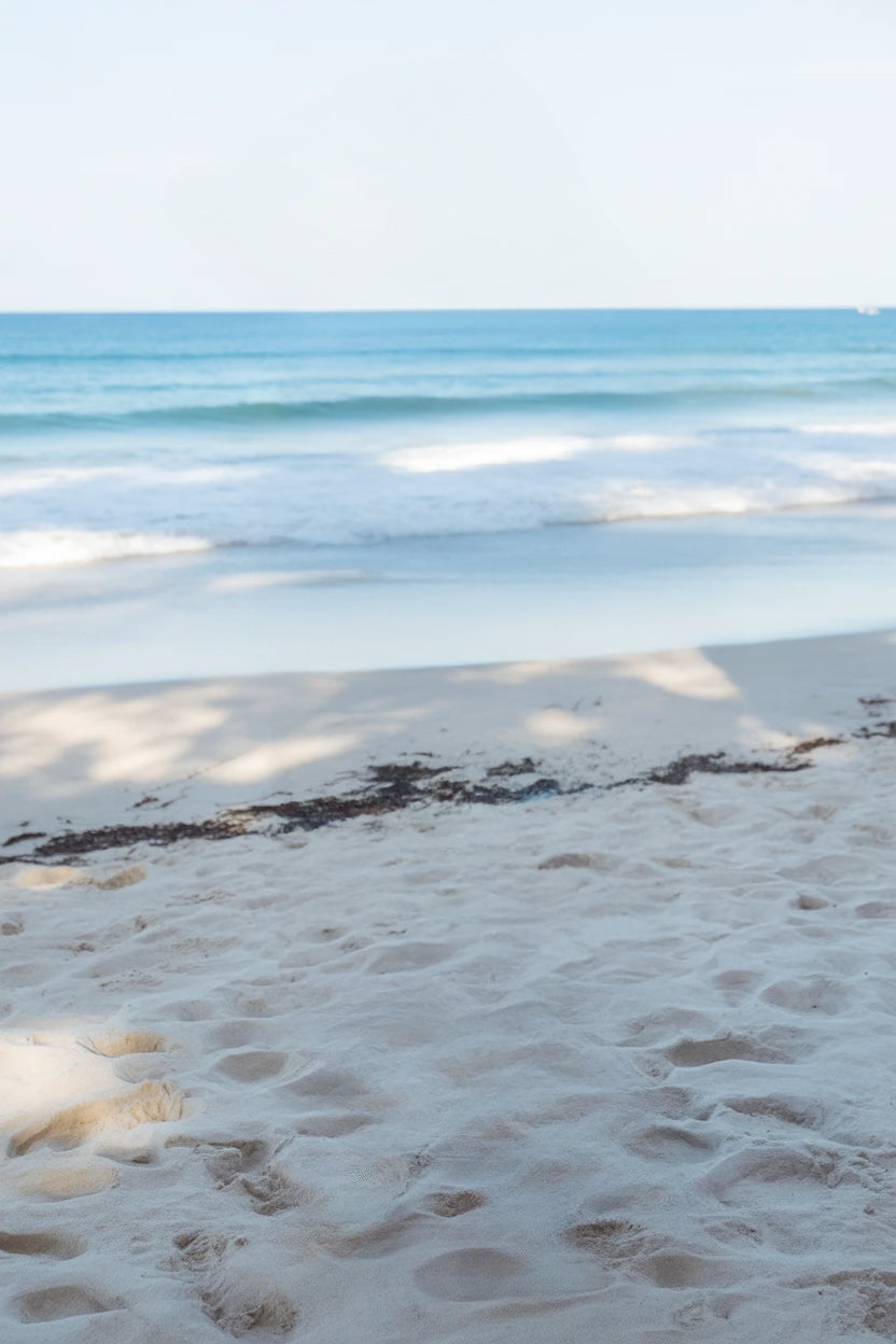 Soft white sand with gentle ocean waves in sunlight