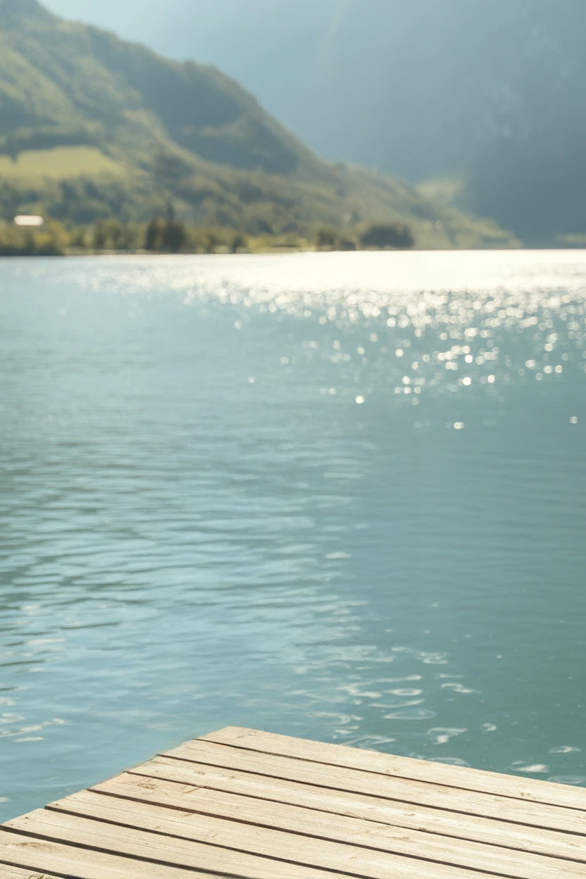 Serene lake view with wooden dock and sunlit mountains