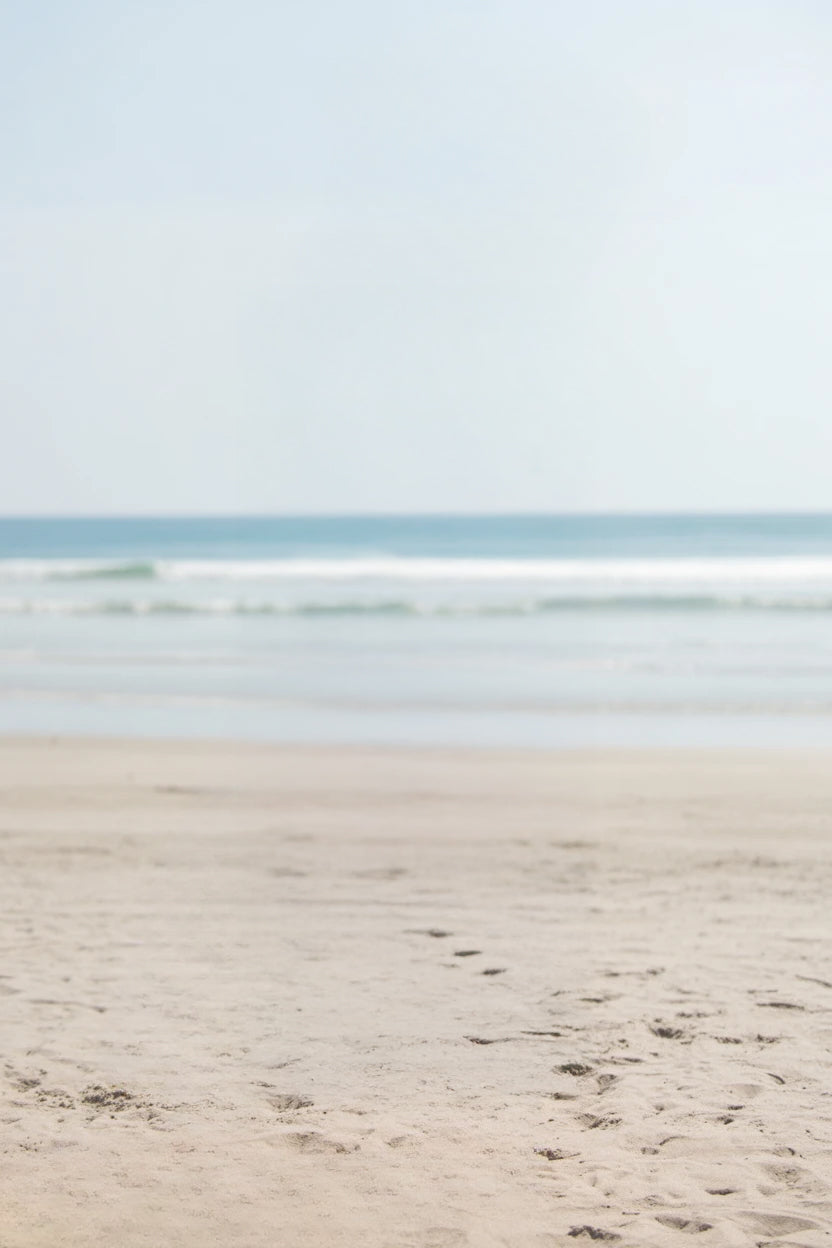 Wide sandy shoreline with gentle ocean waves approaching softly