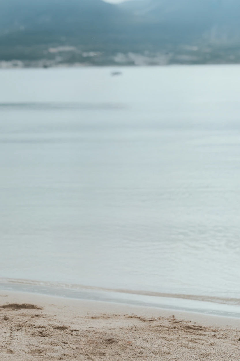 Calm shoreline with soft sand and distant mountain range