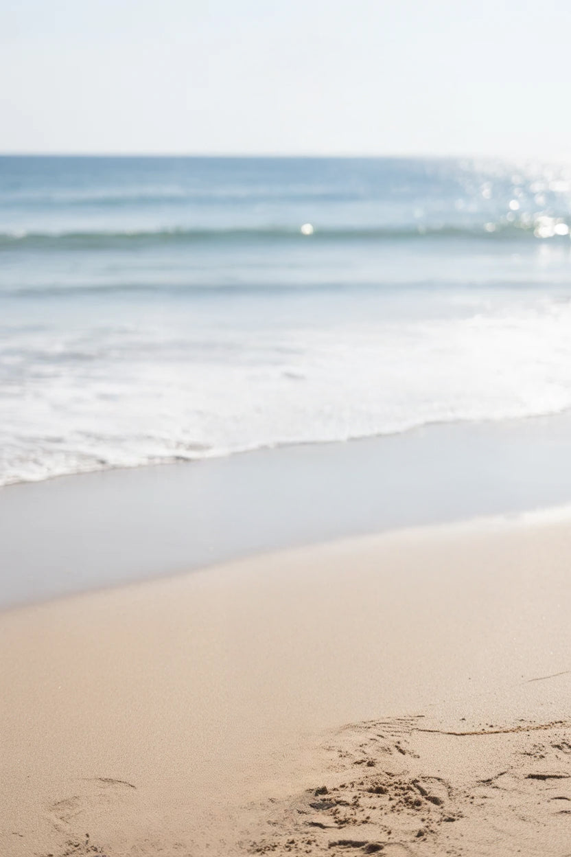 Golden sandy shoreline with gentle ocean waves and sunlight