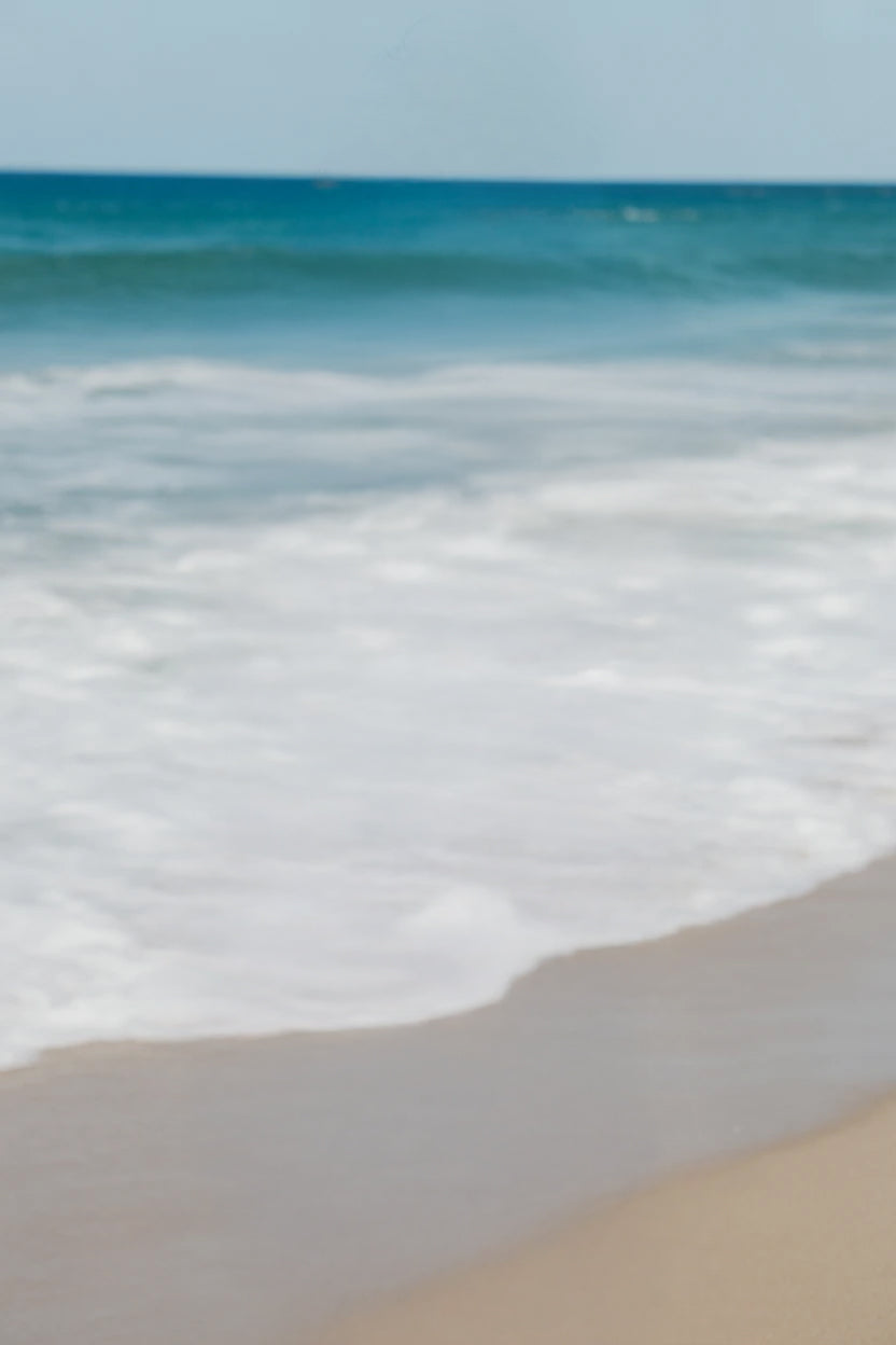 Waves gently rolling onto smooth sandy beach shoreline