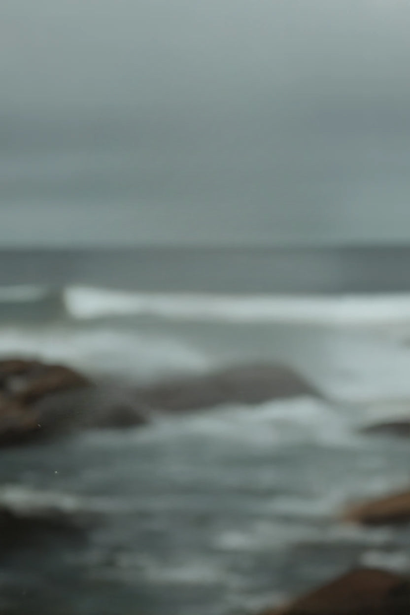 Rocky shoreline with crashing waves under overcast sky