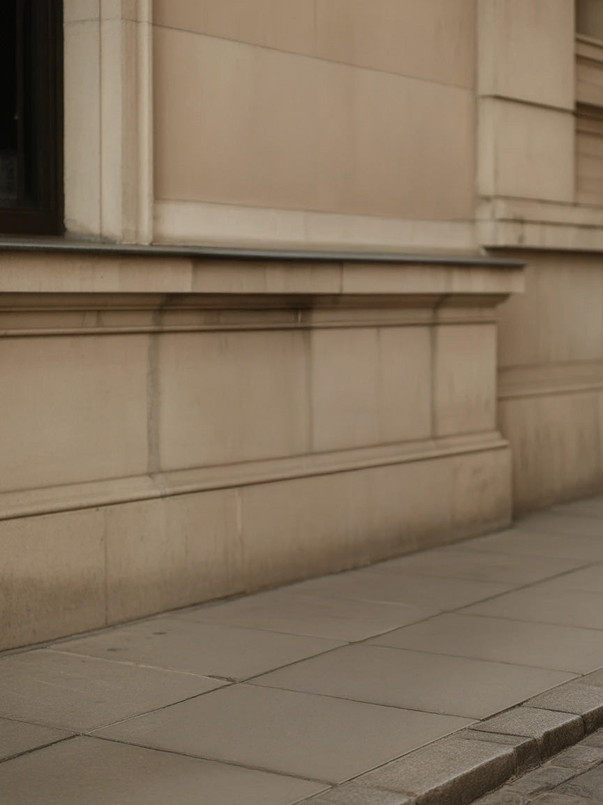 Beige stone building exterior with tiled sidewalk and architectural details