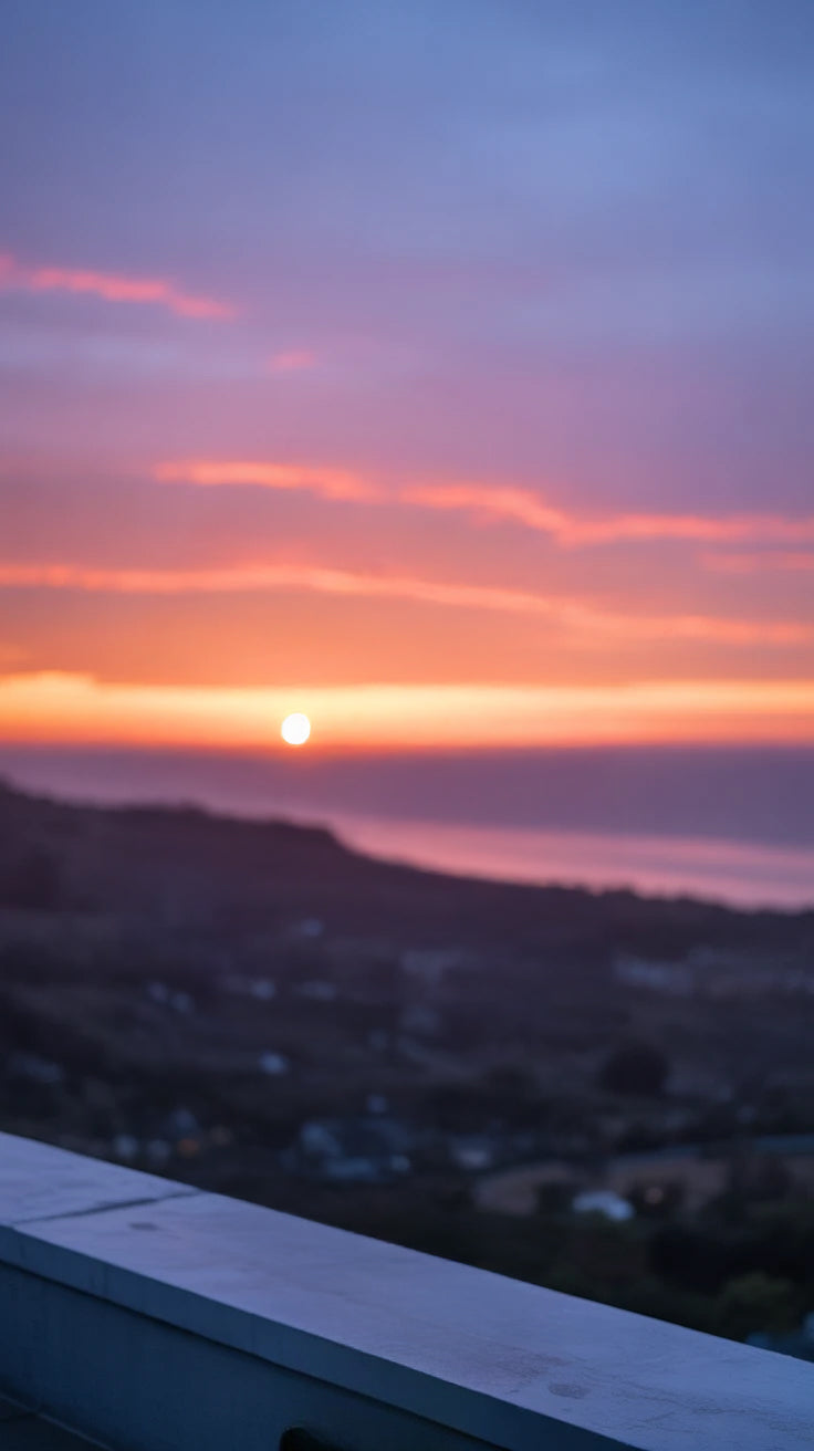 Vibrant sunset over coastal hills and calm ocean horizon