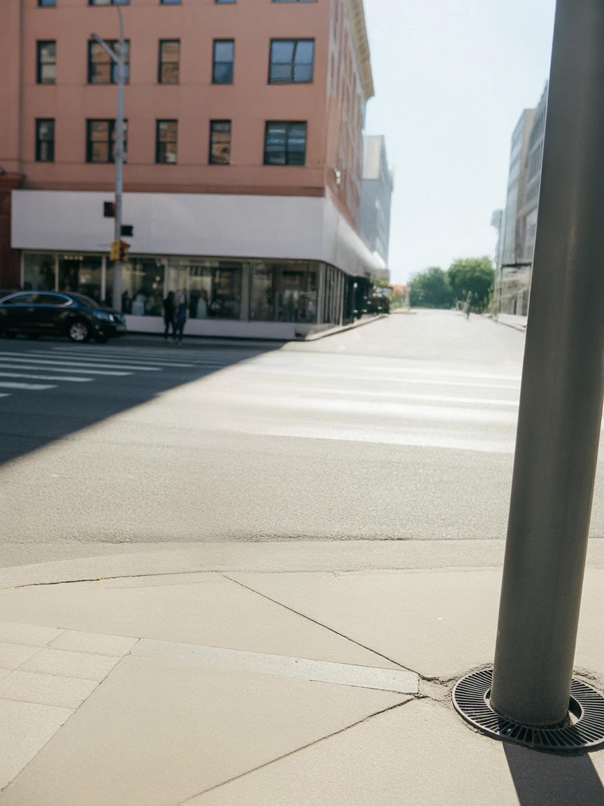 Urban street corner with crosswalk, storefronts, and tall buildings.