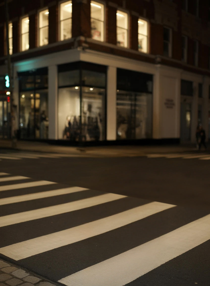 Illuminated city crosswalk beside corner building at night