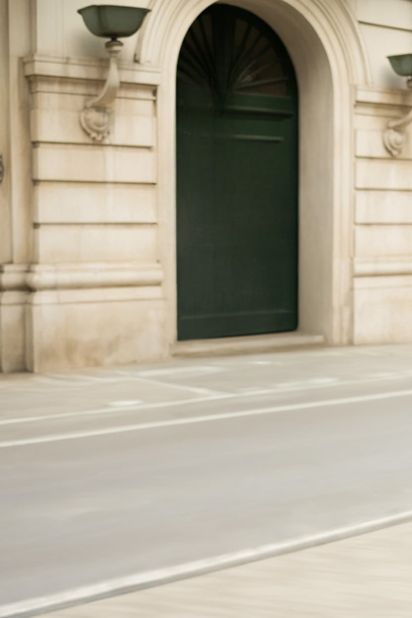Elegant stone building facade with arched doorway and wall lamps.