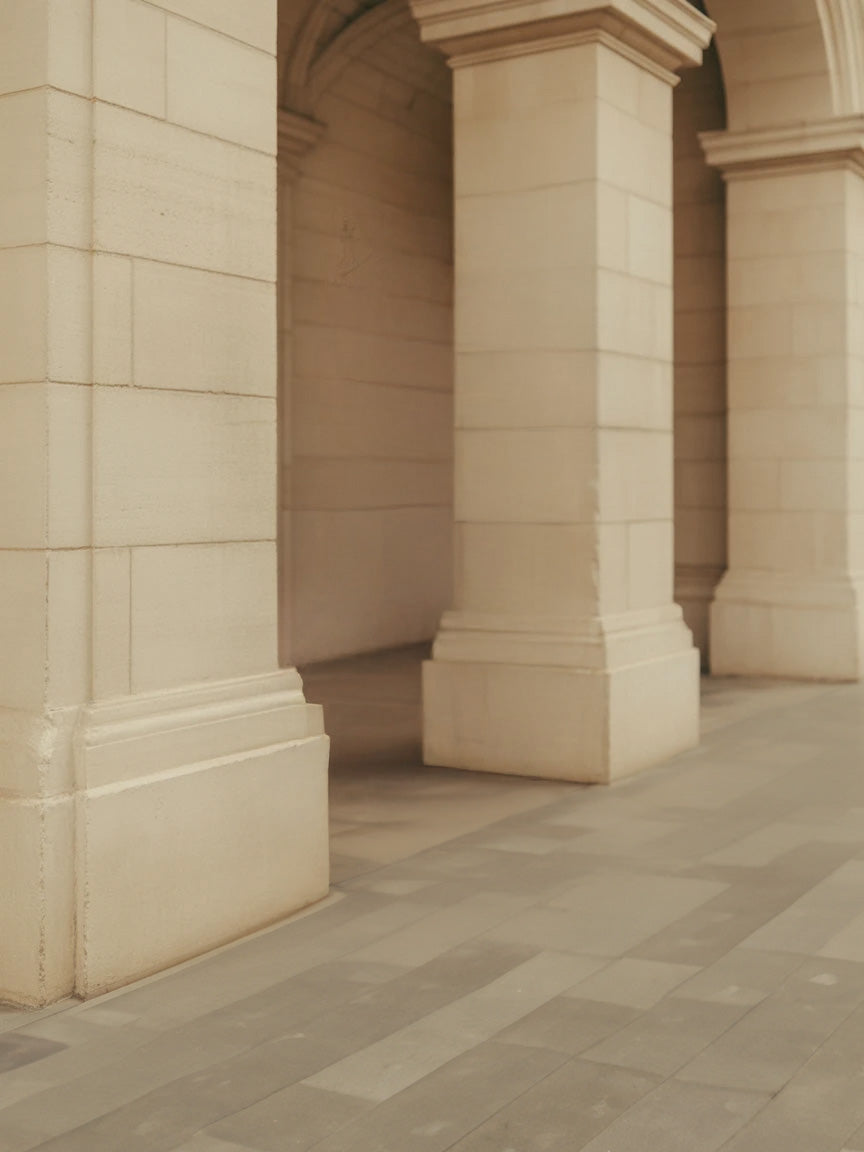 Stone archway corridor with large columns and tiled floor