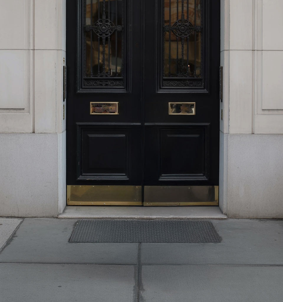 Elegant black double doors with gold accents and stone walls