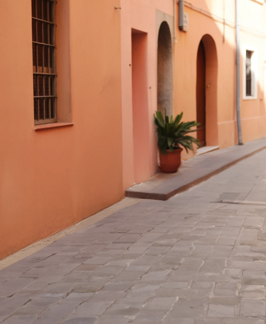 Narrow cobblestone alley with peach walls and arched doorways