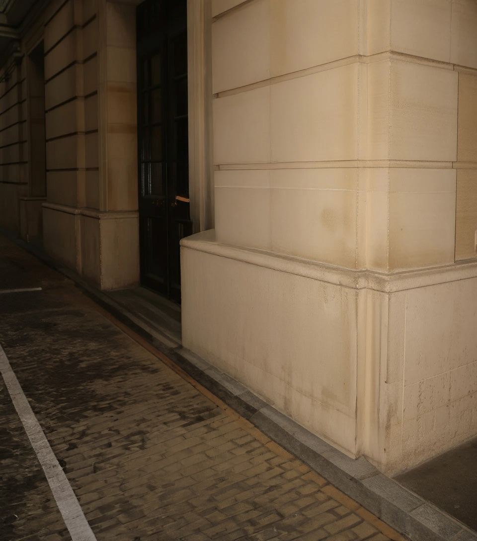 Beige stone building exterior with dark doorway and cobblestone walkway