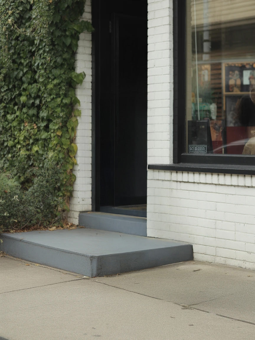Urban storefront entrance with white brick wall and ivy