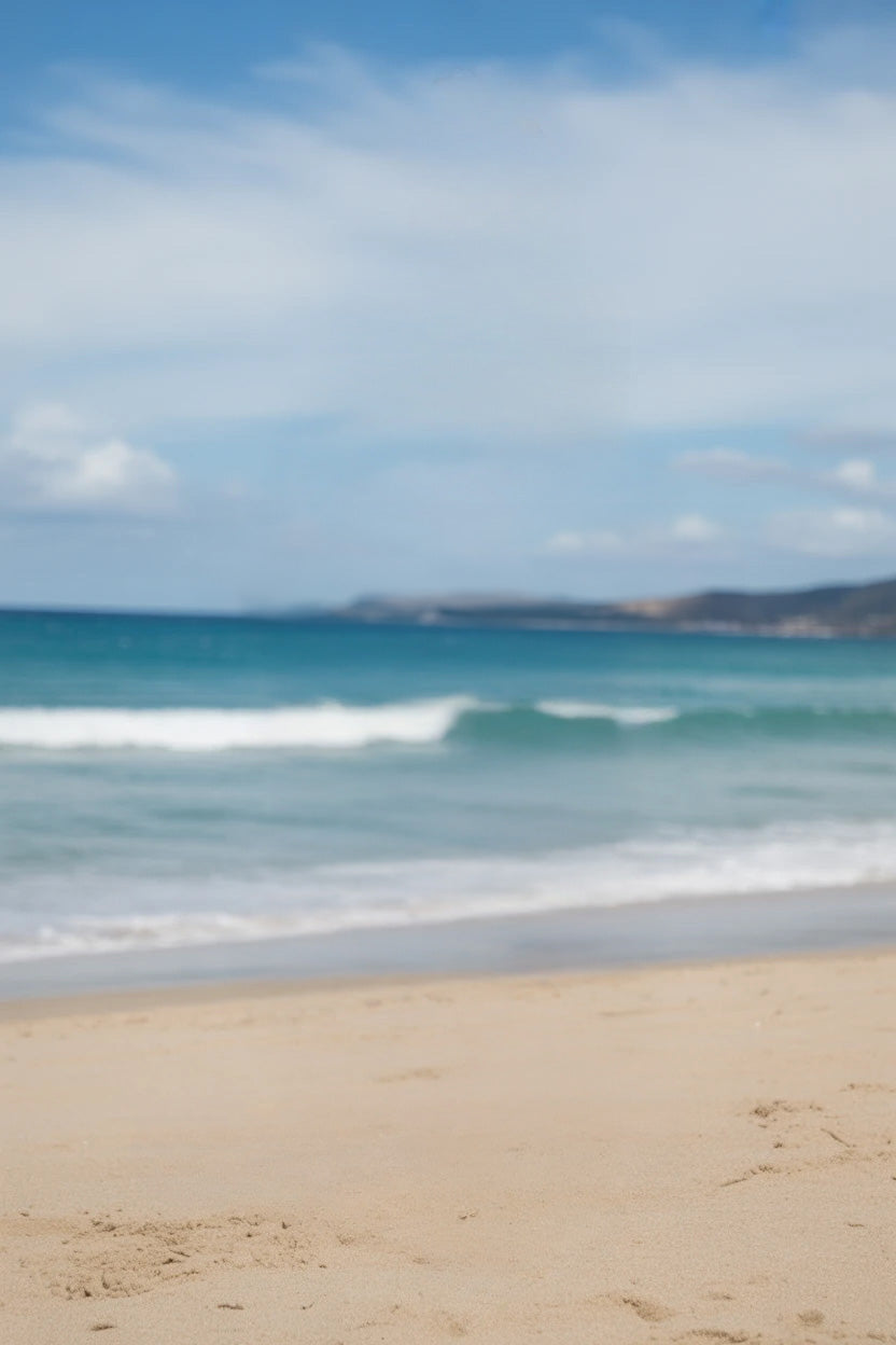 Golden sandy beach with gentle ocean waves and blue sky