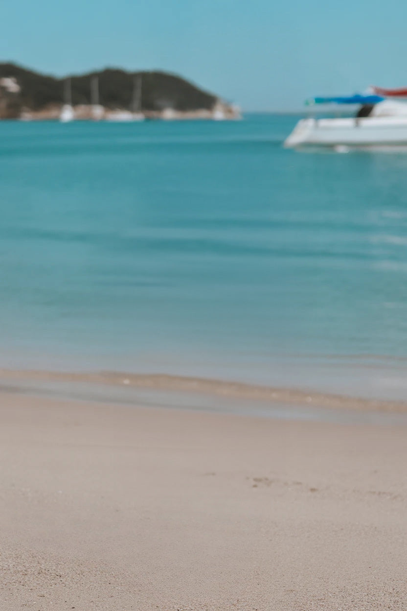 Sunny beach with turquoise water and distant anchored boats