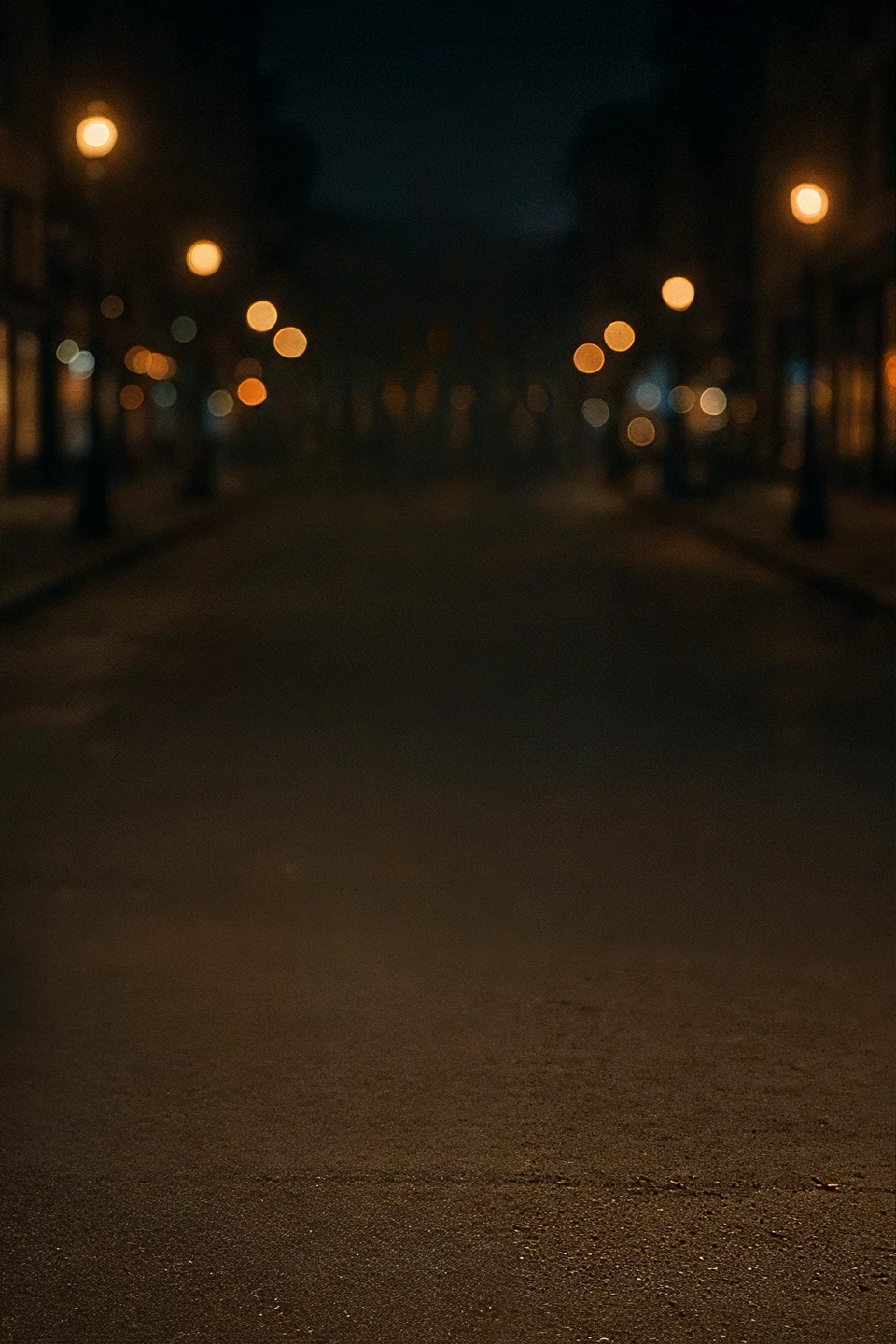 Empty city street at night with glowing lampposts