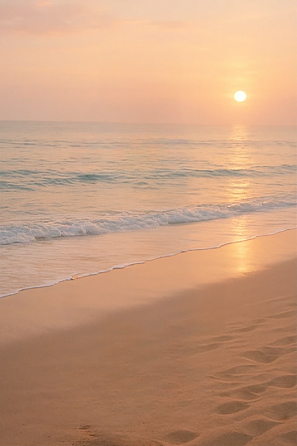 Sunset over calm beach waves and pastel sky