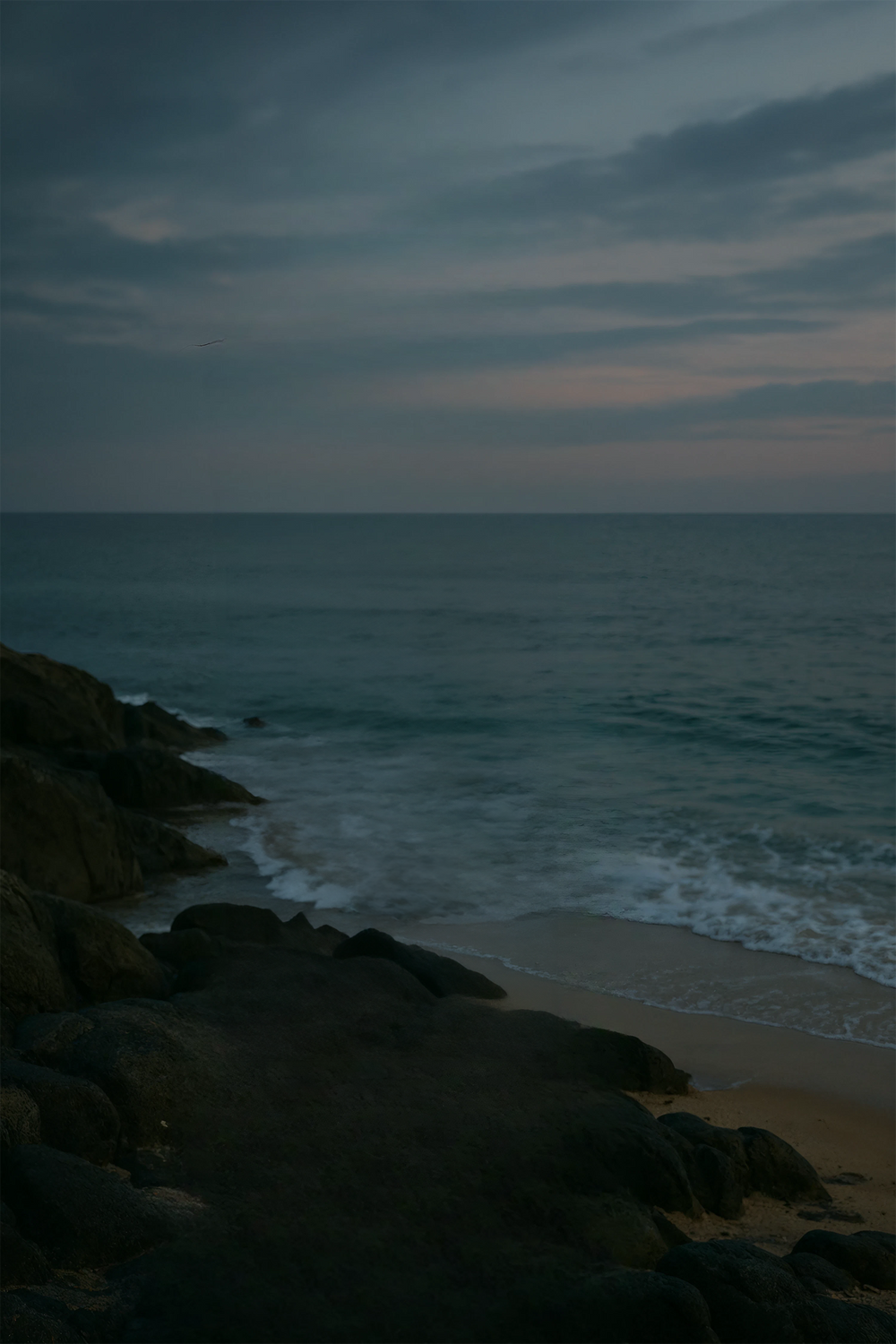 Rocky shoreline with ocean waves under moody evening sky