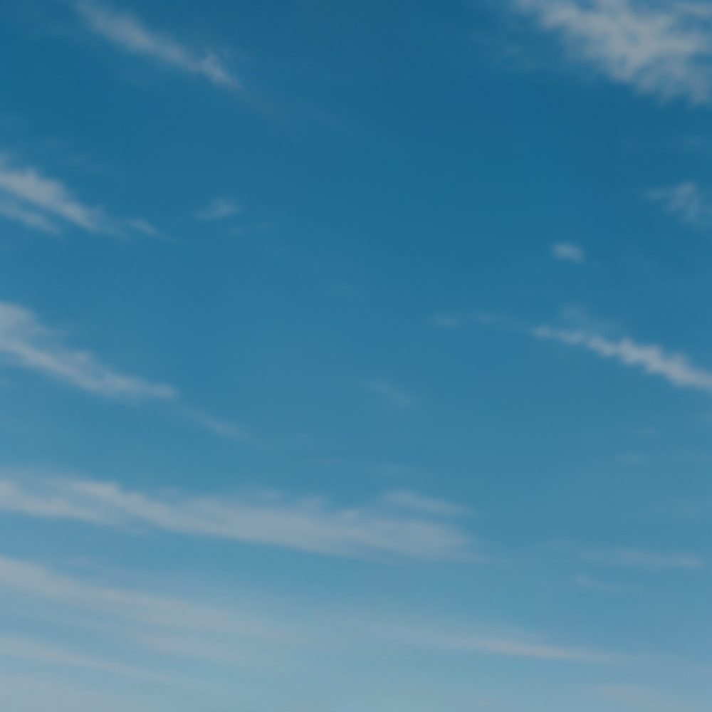 Bright blue sky with scattered white wispy clouds