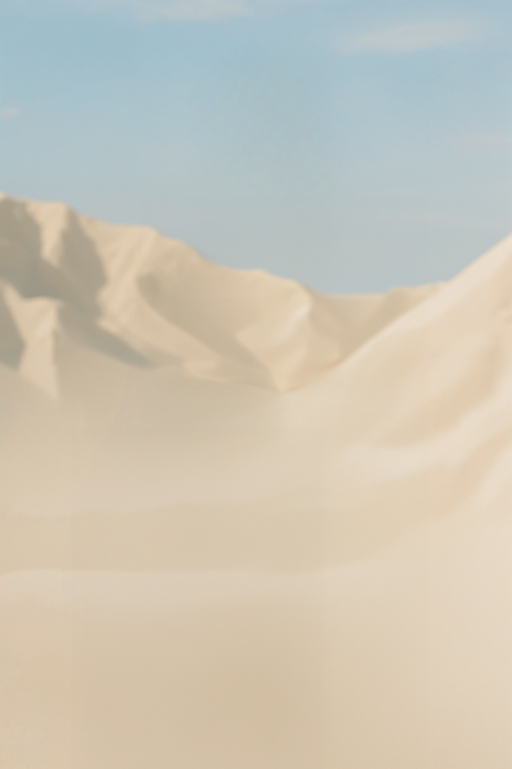 Sunlit sand dunes beneath a soft blue sky