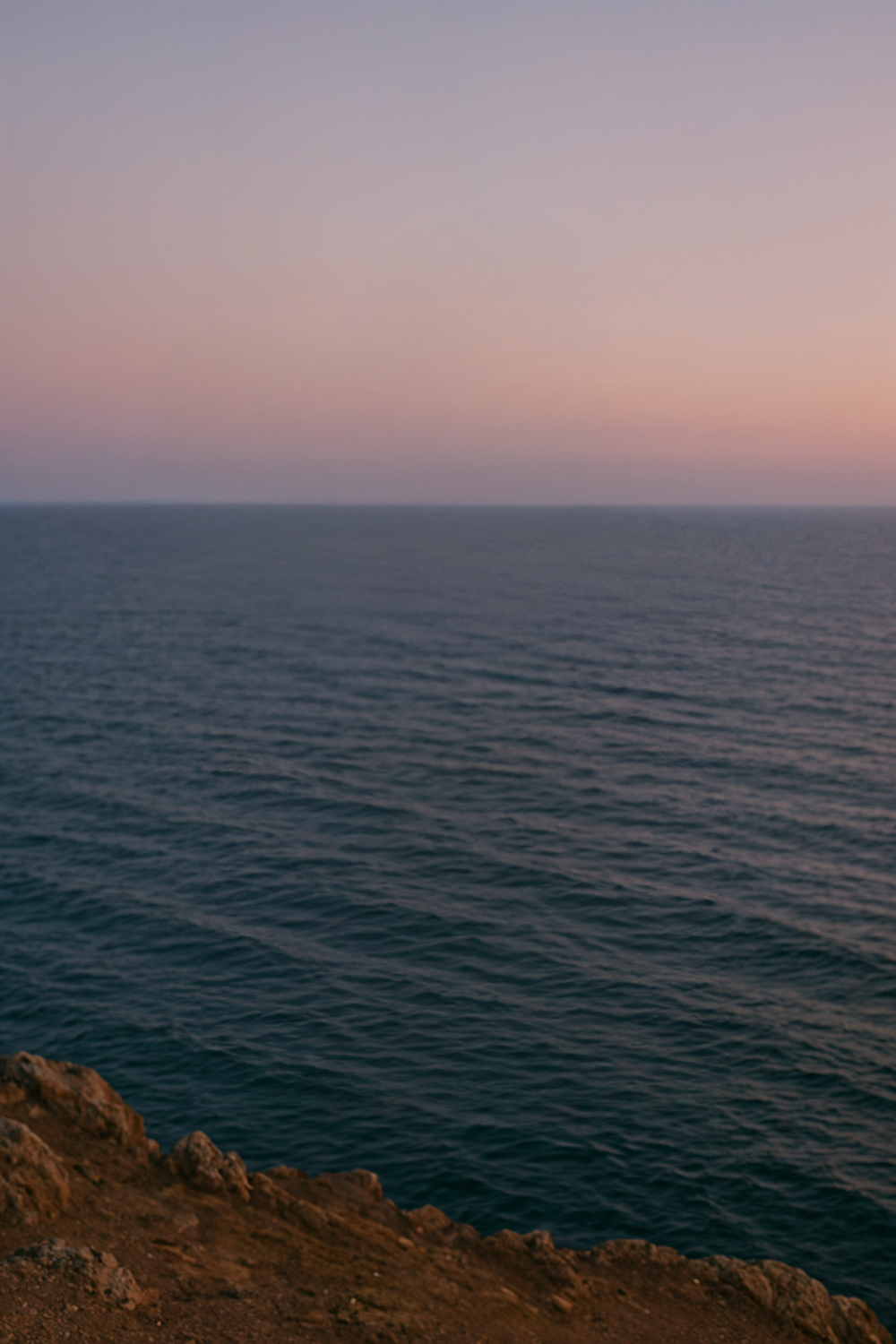 Cliffside ocean view under soft pastel sunset sky